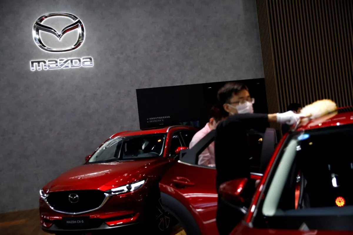 A staff member dusts off a Mazda car at its booth at the Beijing International Automotive Exhibition, in Beijing, China on Sept. 27, 2020. (Tingshu Wang/Reuters)