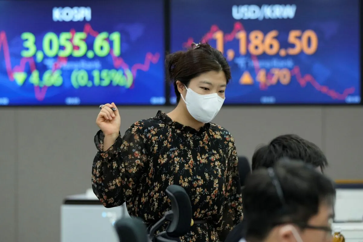 A currency trader works near the screens showing the Korea Composite Stock Price Index (KOSPI), left, and the foreign exchange rate between U.S. dollar and South Korean won at the foreign exchange dealing room of the KEB Hana Bank headquarters in Seoul, South Korea on Sept. 30, 2021. (Ahn Young-joon/AP Photo)