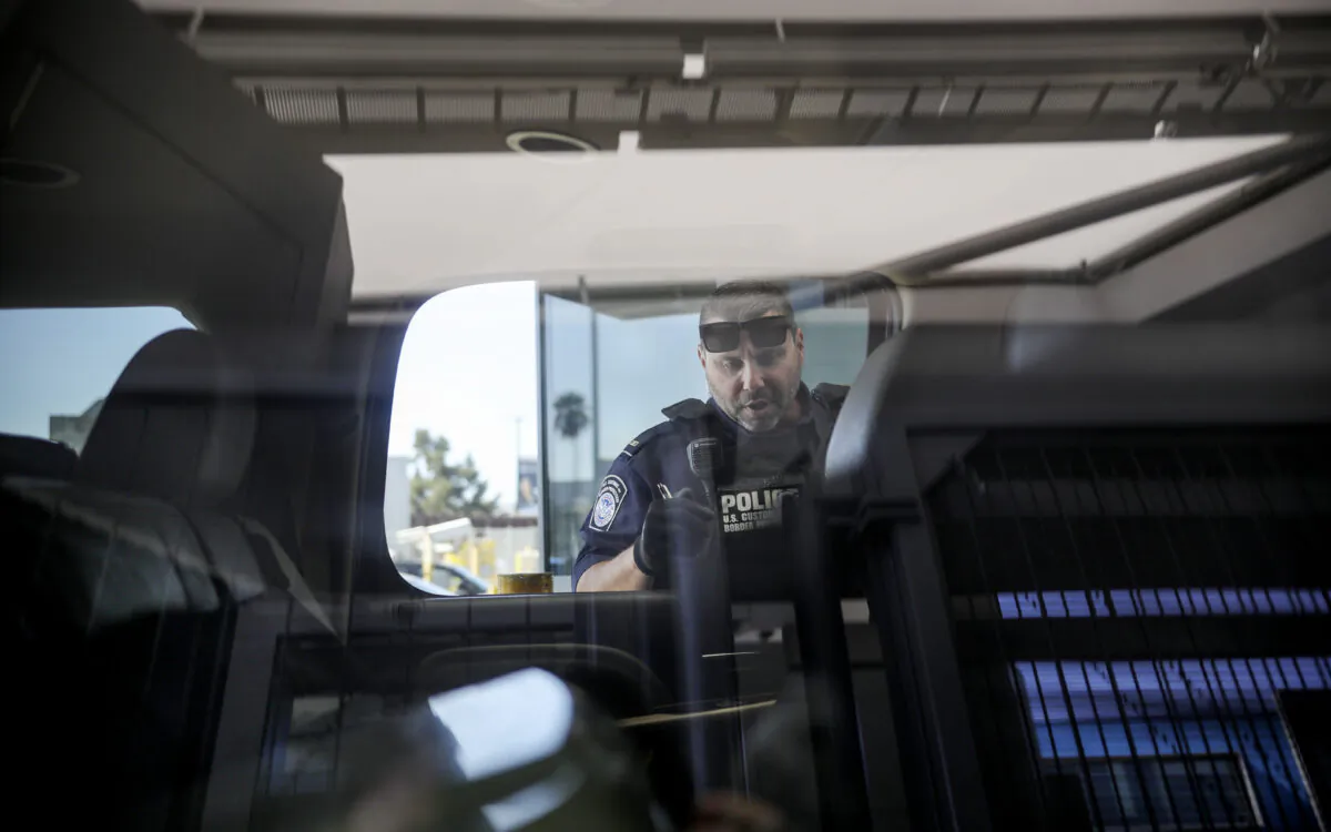 An Immigration and Customs Enforcement (ICE) agent checks an automobile at the U.S.-Mexico border. (File Photo/Sandy Huffaker/AFP via Getty Images)