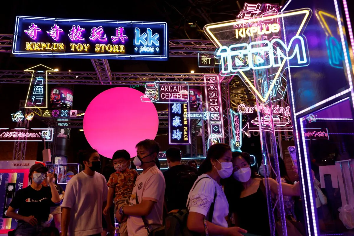 People walk under neon and LED signs at a shopping mall at Mongkok, in Hong Kong on Aug. 8, 2021. (Tyrone Siu/Reuters)