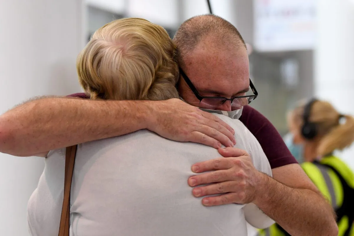 Travellers arriving on the first quarantine free international flights are embraced by family at Sydney International Airport on Nov. 1, 2021. (AAP Image/Bianca De Marchi) 