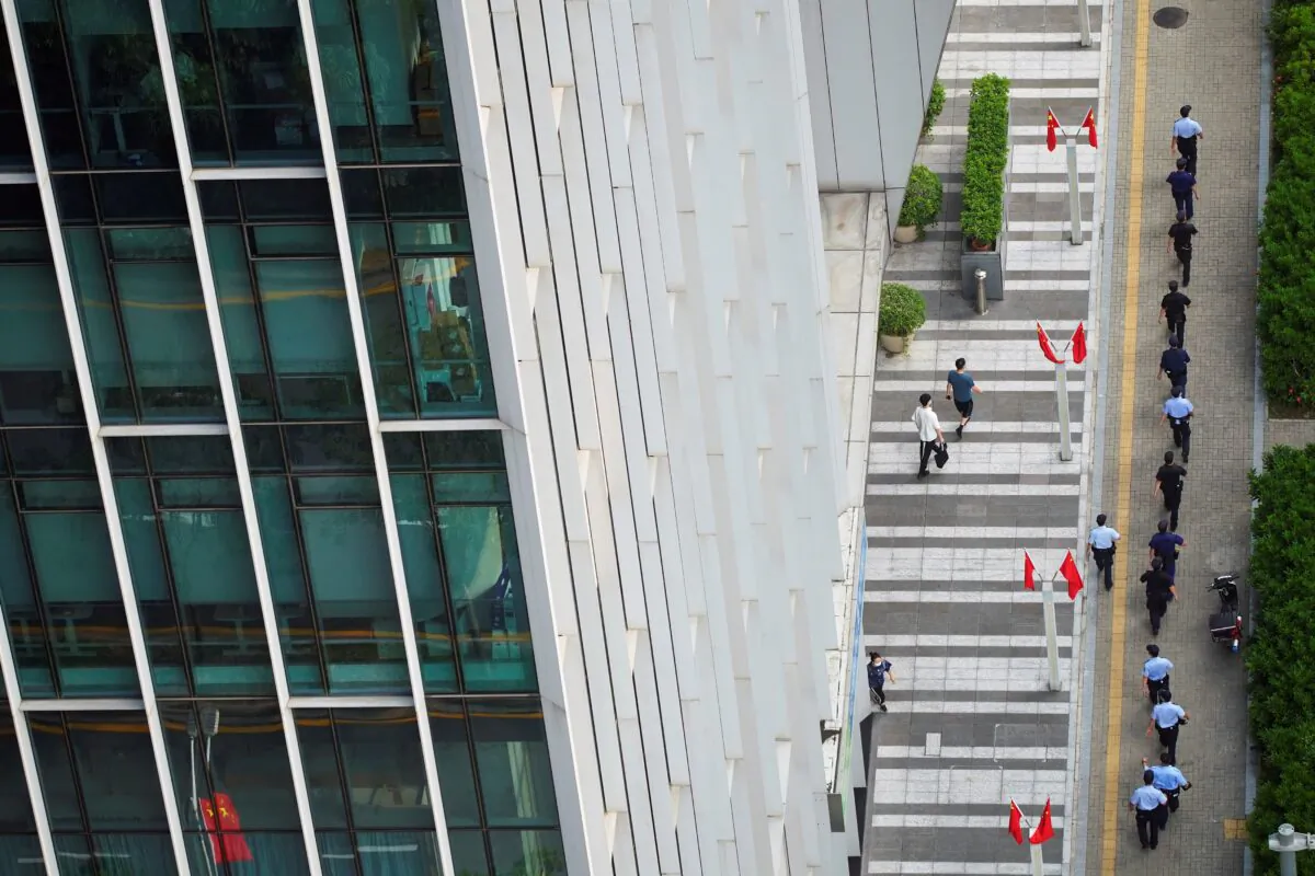 Police officers and security personnel walk outside the headquarters of China Evergrande Group in Shenzhen, Guangdong province, China, on Sept. 30, 2021. (Aly Song/Reuters)