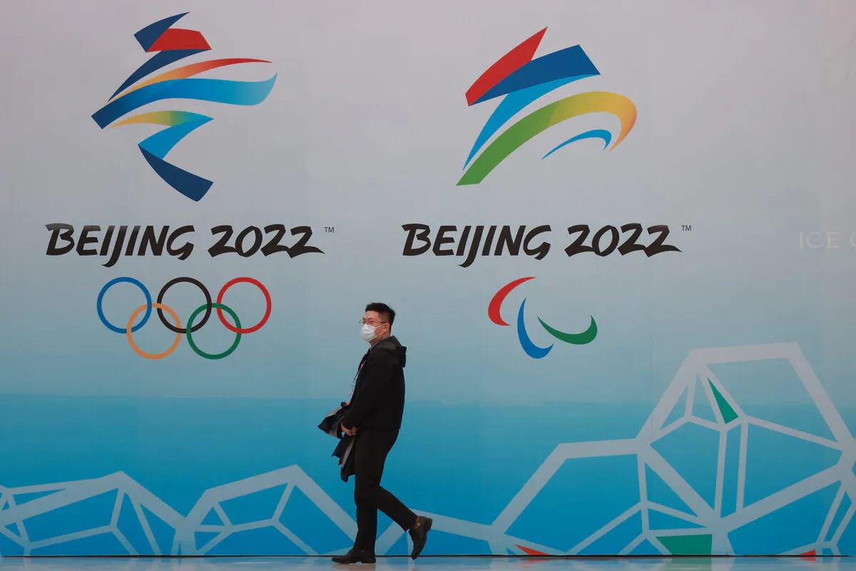 A Chinese man wears a protective mask as he walk in front the logos of the 2022 Beijing Winter Olympics at National Aquatics Centre in Beijing on April 9, 2021. (Lintao Zhang/Getty Images)