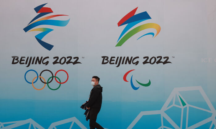 A Chinese man wears a protective mask as he walk in front the logos of the 2022 Beijing Winter Olympics at National Aquatics Centre in Beijing on April 9, 2021. (Lintao Zhang/Getty Images)