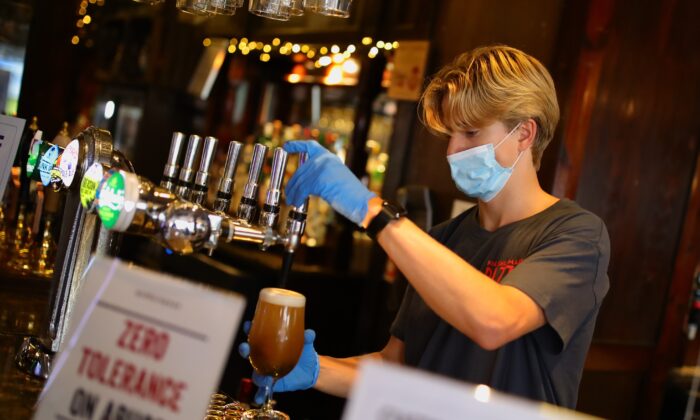 Bar staff in PPE pour drinks at the reopening The Toll Gate, a Wetherspoons pub in Hornsey, north London, as COVID-19 lockdown restrictions are eased across England on July 4, 2020. (Aaron Chown/PA)