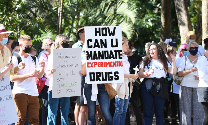 Protesters hold up signs as they march across Victoria Bridge during a rally against a mandatory Covid-19 vaccine in Brisbane, Australia, on Oct. 1, 2021. (Dan Peled/Getty Images)