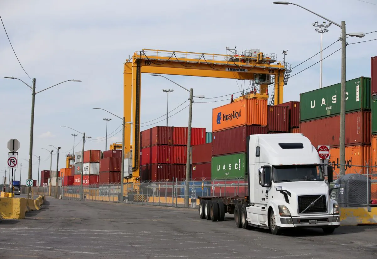 A truck moves past stacked shipping containers at the Port of Montreal in Montreal, Quebec, Canada on May 17, 2021. (Christinne Muschi/Reuters)