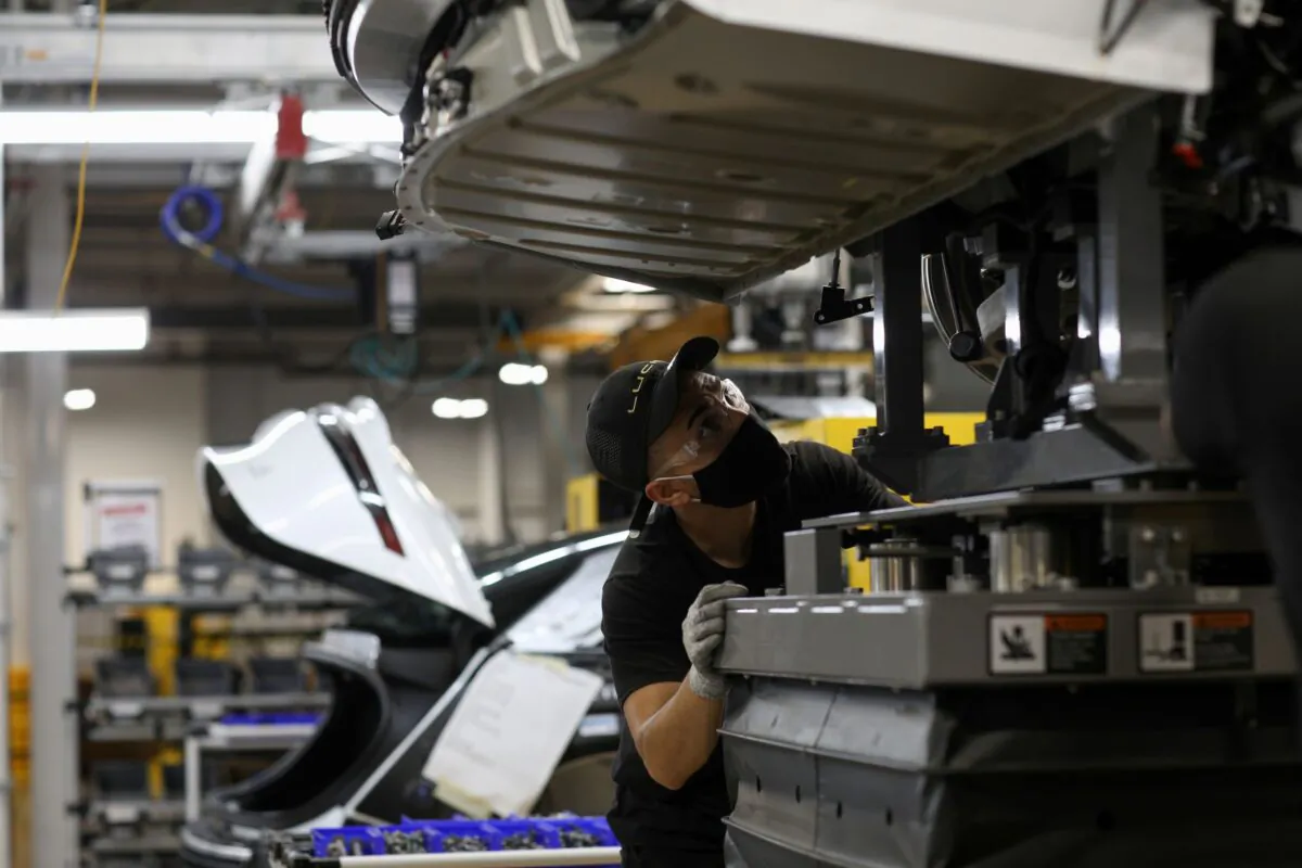 A worker looks to marry the body structure with the battery pack and the front and rear sub frames as they assemble electric vehicles at the Lucid Motors plant in Casa Grande, Ariz., on Sept. 28, 2021. (Caitlin O'Hara/Reuters)