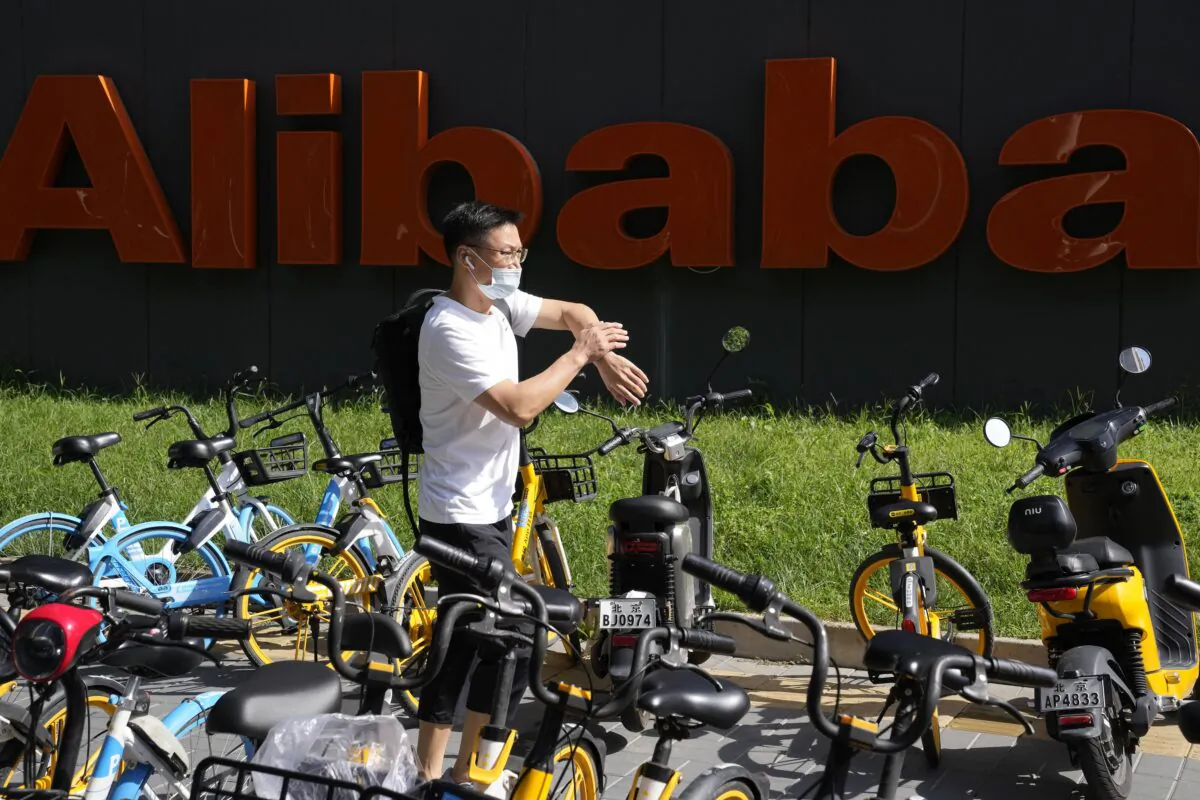 A man passes by the logo for Alibaba outside the Beijing headquarters in Beijing, China, on Aug. 24, 2021. (Ng Han Guan/AP Photo)
