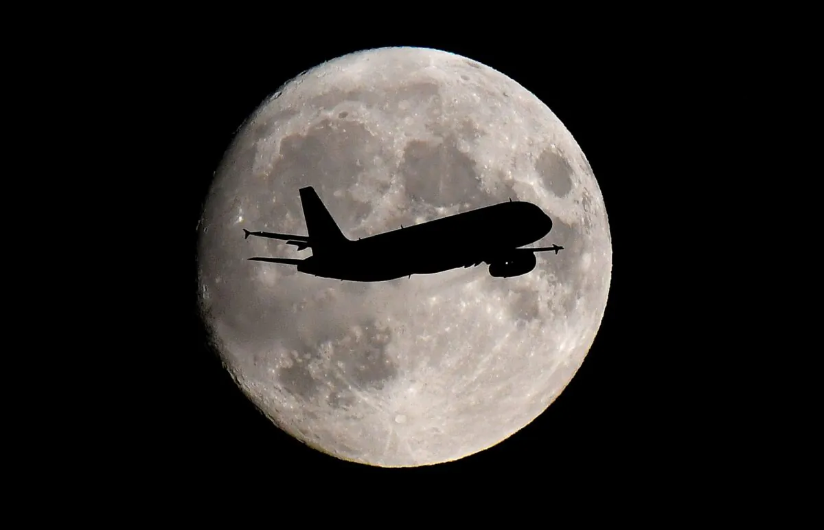 A passenger plane passes in front of the moon as it makes its final landing approach to Heathrow Airport in London, Britain, on Sept. 12, 2019. (Toby Melville/Reuters)
