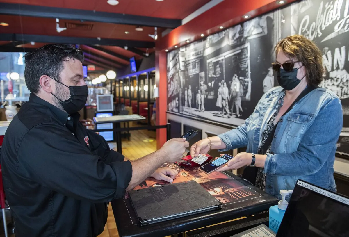 A woman’s COVID-19 QR code is scanned at a restaurant in Montreal on Sept. 1, 2021. (The Canadian Press/Graham Hughes)