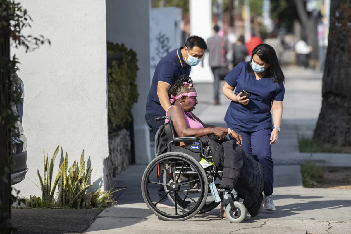 Medical staff assist a disabled homeless woman in front of the Alvarado Care Center in Los Angeles, Calif., on Sept. 29, 2021. (John Fredricks/The Epoch Times)