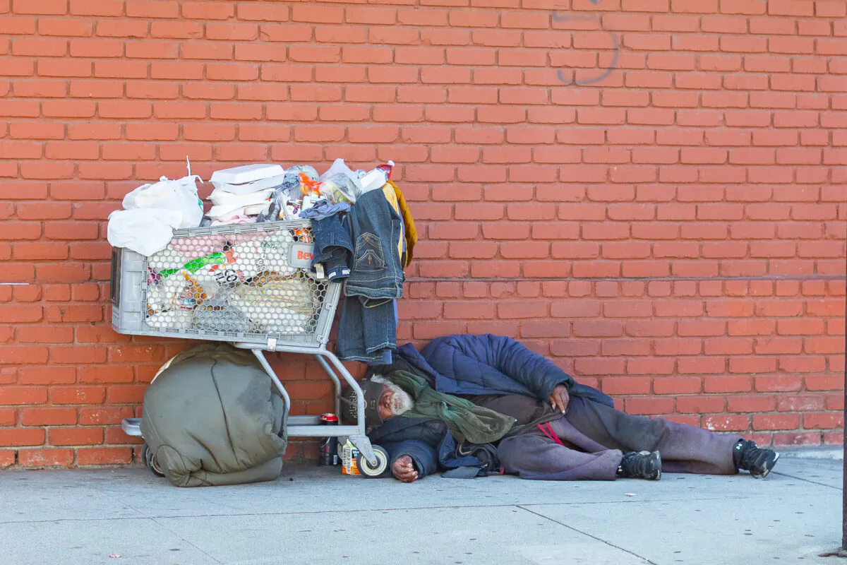 A homeless man sleeps on a sidewalk in Long Beach on Feb. 26, 2021. (John Fredricks/The Epoch Times)