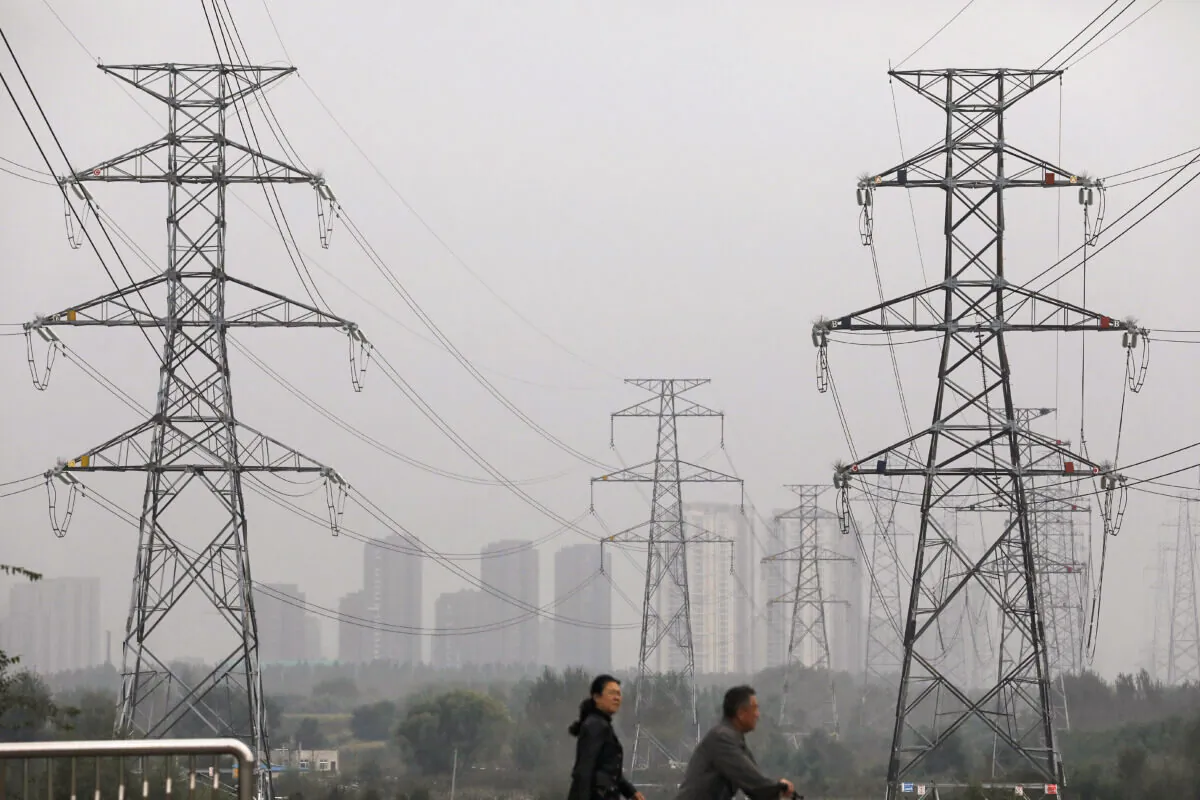 People walk past electricity pylons in Shenyang, Liaoning province, China September 29, 2021. (REUTERS/Tingshu Wang)