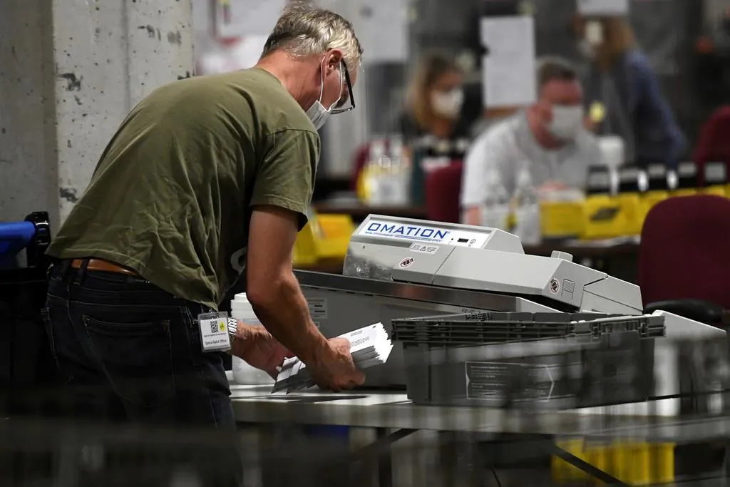 A worker uses a envelope cutting machine as they open special ballots from national, international, Canadian Forces and incarcerated electors at Elections Canada's distribution centre in Ottawa on election night of the 44th Canadian general election, on Sept. 20, 2021. (The Canadian Press/Justin Tang)