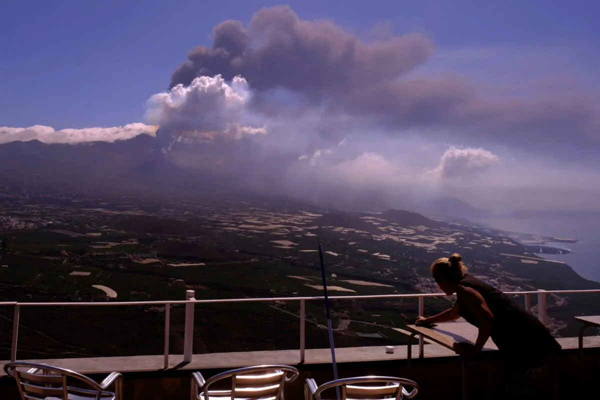 A worker cleans the ash from the tables of a restaurant as lava flows from a volcano on the Canary Island of La Palma, Spain, on Oct. 4, 2021. (Daniel Roca/AP Photo)