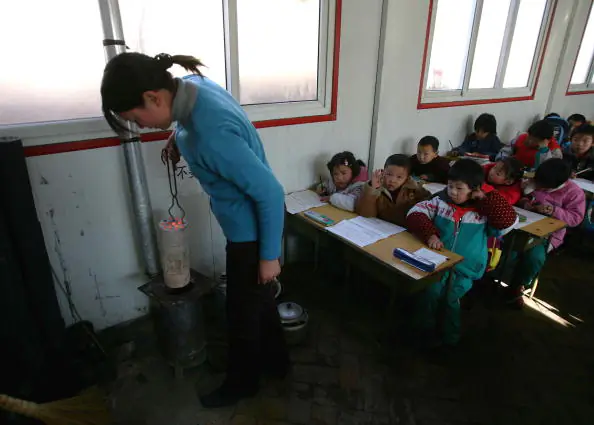 A teacher prepares a stove to furnish heat for a classroom at Xingzhi Primary School, one of the largest migrant children's schools in Beijing, China, on Dec. 28, 2004. (Cancan Chu/Getty Images)