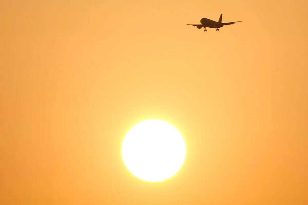 A passenger aircraft flies past the sun at sunset in Malaga, southern Spain, on Aug. 3, 2018. (Jon Nazca/Reuters)