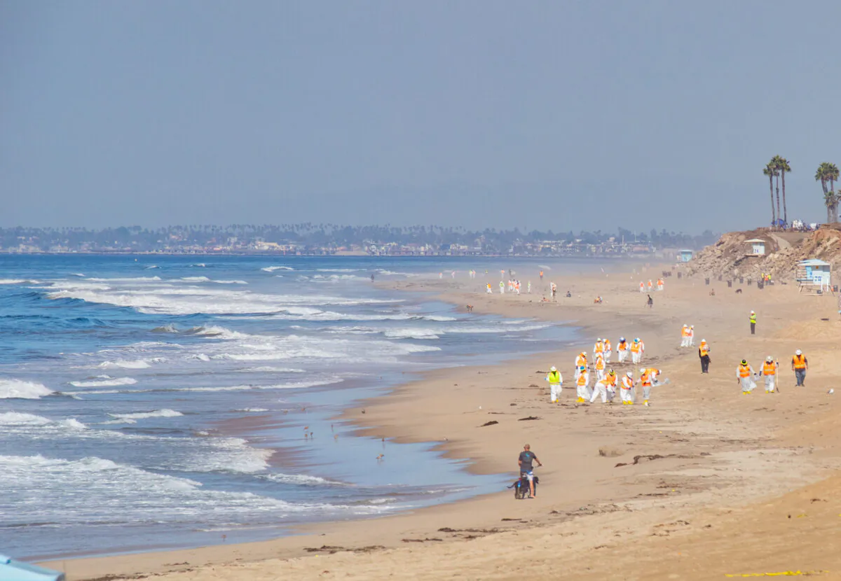 Workers clean an oil spill along the coastline in Huntington Beach, Calif., on Oct. 5, 2021. (John Fredricks/The Epoch Times)