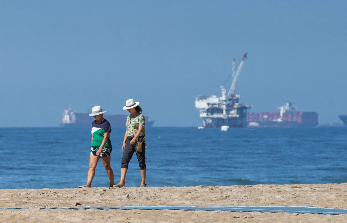 Residents walk along the beach in Huntington Beach, Calif., on Oct. 5, 2021, near the site of a recent massive oil spill. (John Fredricks/The Epoch Times)