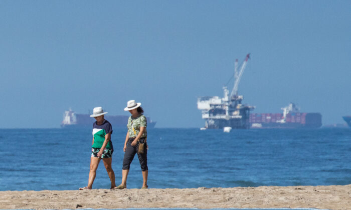 Residents walk along the beach in Huntington Beach, Calif., on Oct. 5, 2021, near the site of a recent massive oil spill. (John Fredricks/The Epoch Times)