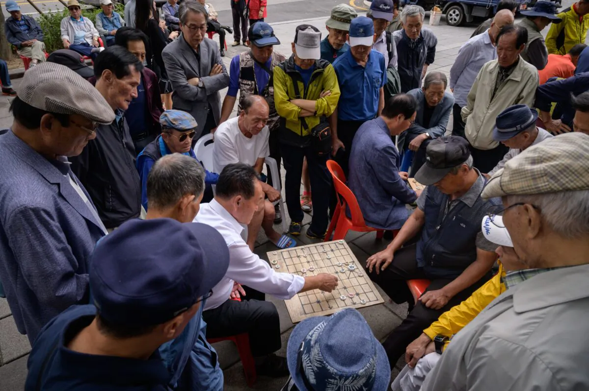 Two men play a board game as they are surrounded by a group of spectators, on a street in Seoul on Sept. 20, 2019. (Ed Jones/AFP via Getty Images)