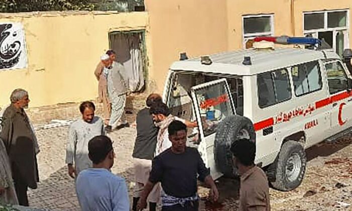 Afghan men stand next to an ambulance after a bomb attack at a mosque in Kunduz, Afghanistan, on Oct. 8, 2021. (AFP via Getty Images)