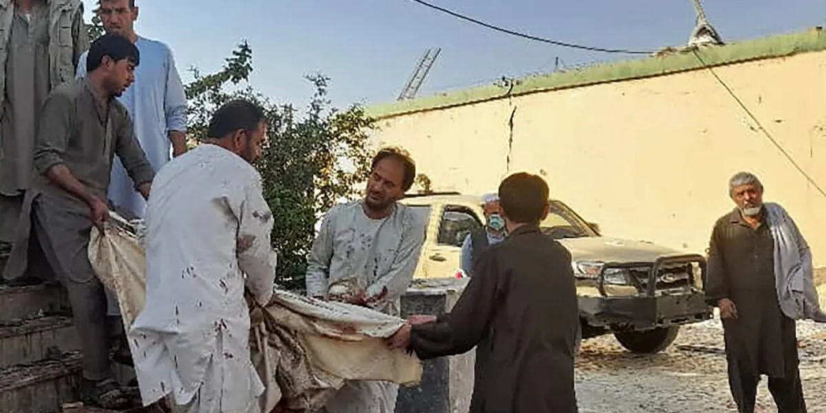 Afghan men carry the dead body of a victim to an ambulance after a bomb attack at a mosque in Kunduz on October 8, 2021. (AFP via Getty Images)