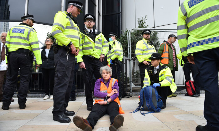 A climate activist from the group Insulate Britain sits on the ground in handcuffs after being arrested by police during a demonstration in which the protesters blocked a roundabout in central London on Oct. 8, 2021. (Daniel Sorabji/ AFP via Getty Images)