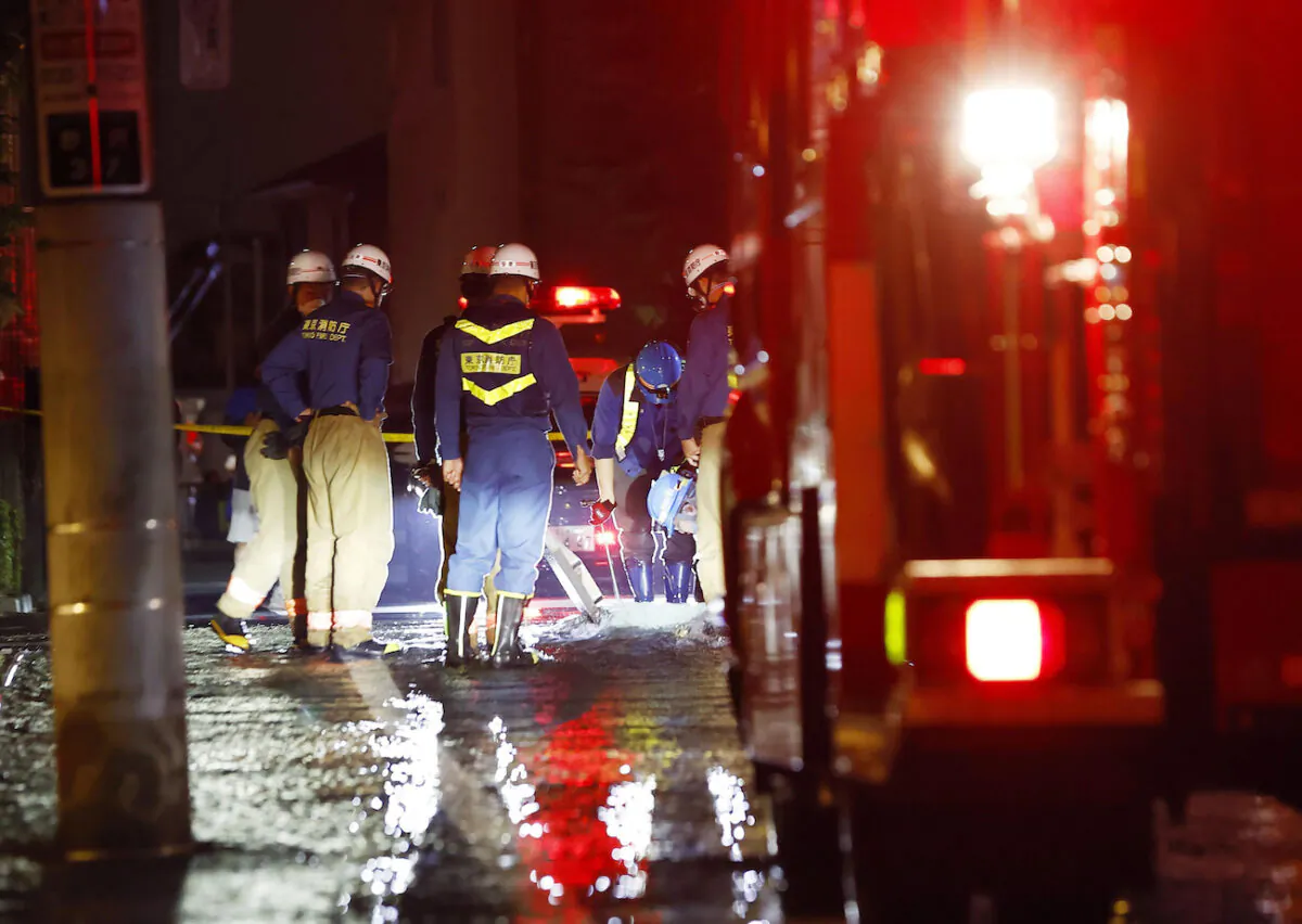 Firefighters work on an inundated road following an earthquake, in Tokyo, on Oct. 8, 2021. (Kyodo News via AP)
