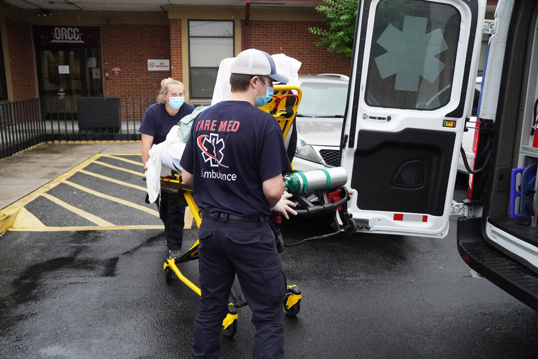 EMS workers Ethan Webber and Bailey Thornton wheel an obese patient to an ambulance in Chattanooga, Tenn., on Oct. 4, 2021. (Jackson Elliott/The Epoch Times)