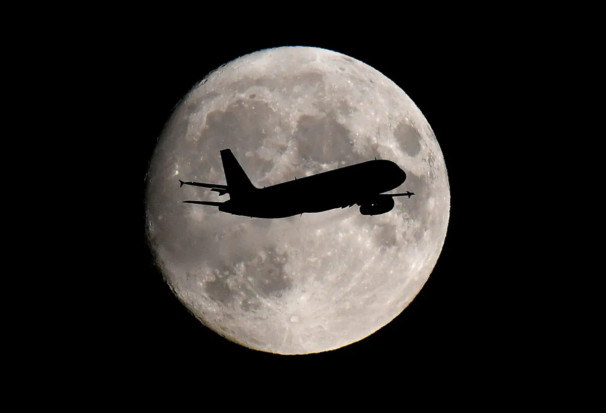 A passenger plane passes in front of the moon as it makes its final landing approach to Heathrow Airport in London, Britain, on Sept. 12, 2019. (Toby Melville/Reuters)