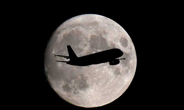 A passenger plane passes in front of the moon as it makes its final landing approach to Heathrow Airport in London, Britain, on Sept. 12, 2019. (Toby Melville/Reuters)