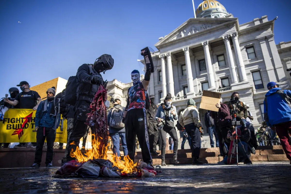 Members of the Communist Party USA and other anti-fascist groups burn an American flag on the steps of the Colorado state Capitol in Denver on Jan. 20, 2021. (Michael Ciaglo/Getty Images)
