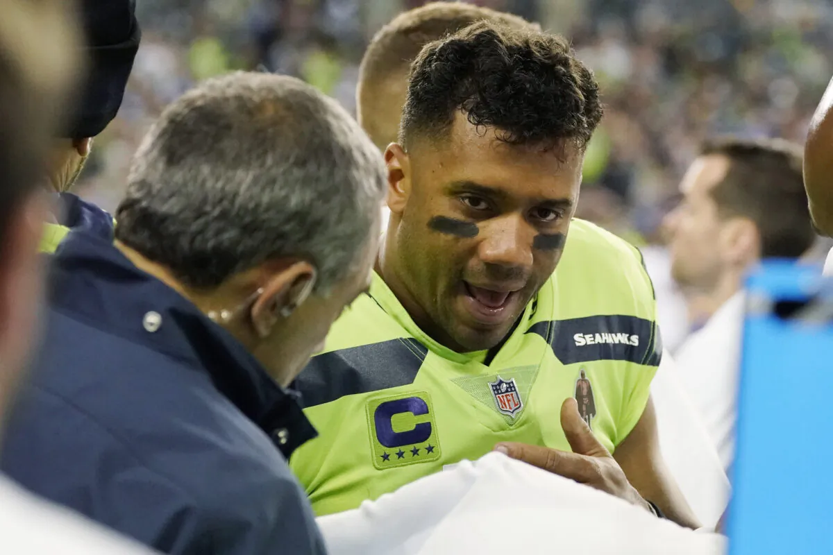 Seattle Seahawks quarterback Russell Wilson has his throwing hand examined on the sideline during the second half of an NFL football game against the Los Angeles Rams, in Seattle, Wash., on Oct. 7, 2021. (Elaine Thompson/AP Photo)
