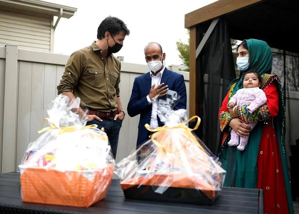 Prime Minister Justin Trudeau speaks with Obaidullah Rahimi, his wife Arezoo, and daughter Hawa, 2 months, after assembling care packages for the recently resettled Afghan family for Thanksgiving in Ottawa, on Oct. 9, 2021. (The Canadian Pree/Justin Tang)