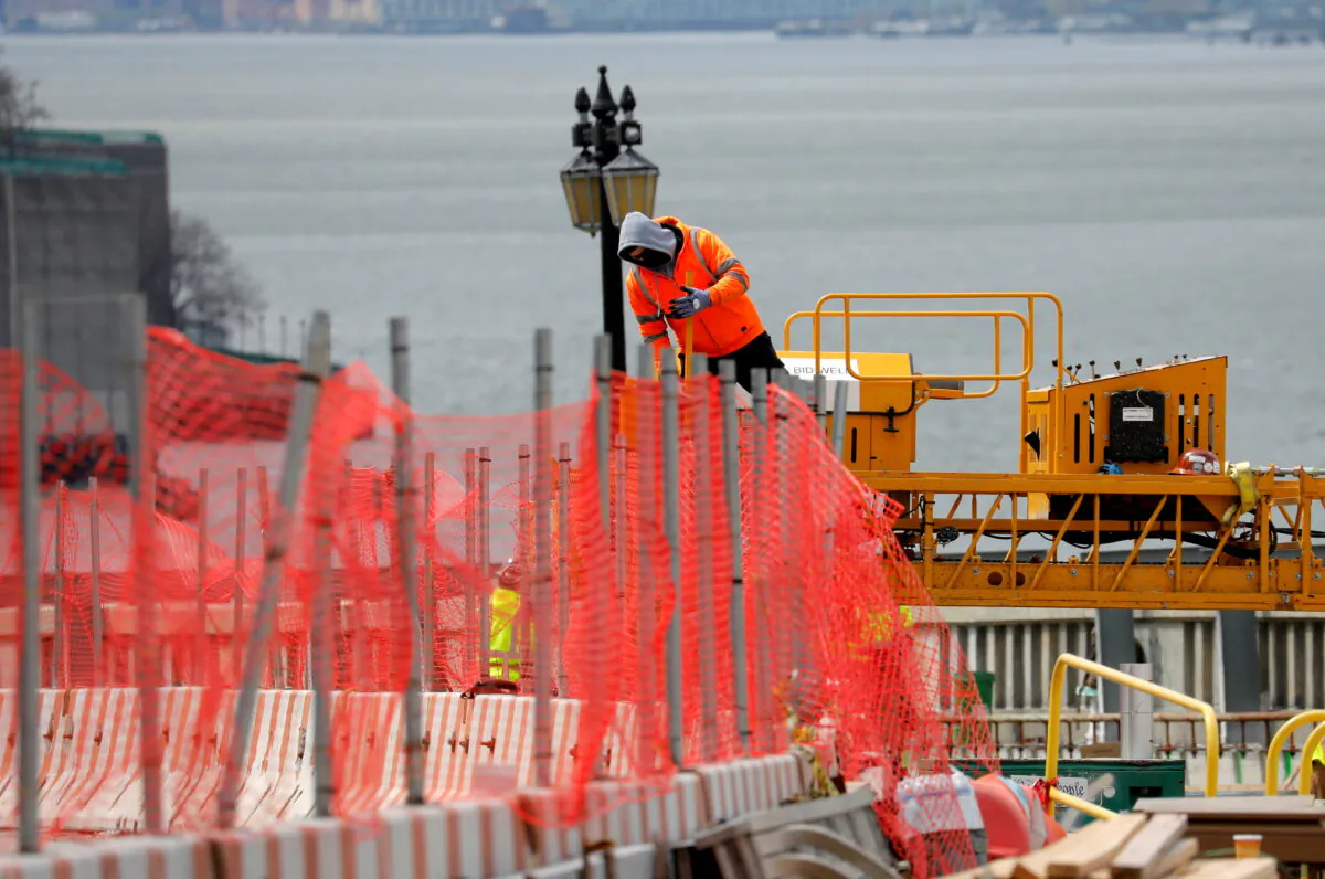 A construction worker climbs above a line of fencing at the site of a large public infrastructure reconstruction project of an elevated roadway and bridges in upper Manhattan in New York on April 22, 2021. (Mike Segar/Reuters)