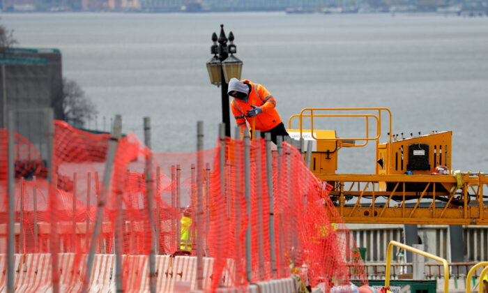 A construction worker climbs above a line of fencing at the site of a large public infrastructure reconstruction project of an elevated roadway and bridges in upper Manhattan in New York on April 22, 2021. (Mike Segar/Reuters)