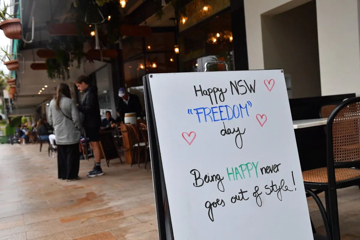 Signage about Freedom day as diners sit at a café in Bronte, Sydney, Australia, on Oct. 11, 2021. (AAP Image/Joel Carrett)