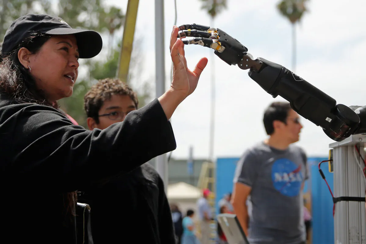 A woman reaches to touch a robotic arm developed by the Johns Hopkins University Applied Physics Laboratory on display at the Defense Advanced Research Projects Agency (DARPA, the Pentagon's science research group) Robotics Challenge Expo at the Fairplex in Pomona, California, on June 6, 2015. (Chip Somodevilla/Getty Images)