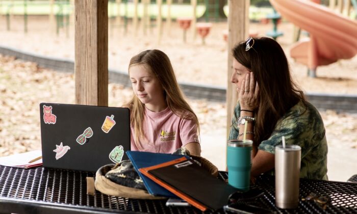 Lillian Hickey (L) does school work with her mom at a park in Alachua County, Florida, on Oct. 12, 2021. (Amber Dorn for The Epoch Times)