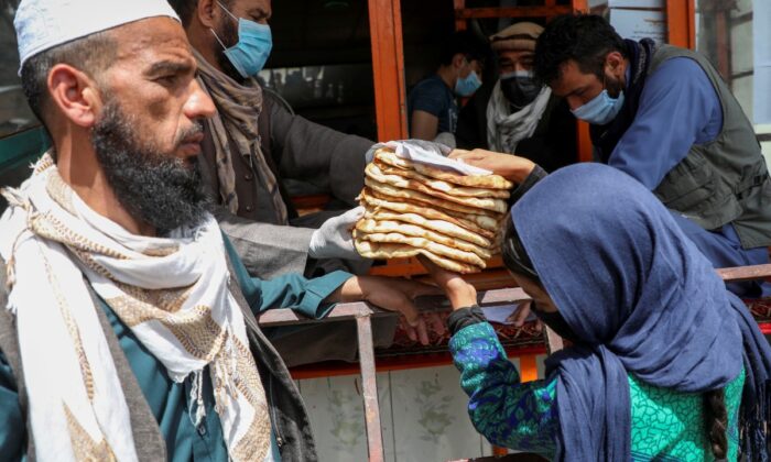 An Afghan girl receives free bread distributed by the government, outside a bakery, in Kabul, Afghanistan, on May 3, 2020. (Omar Sobhani/Reuters)