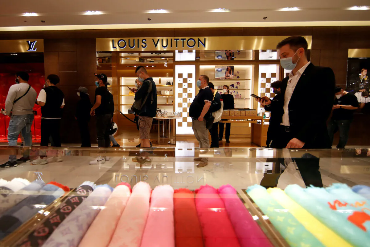 Clients, wearing face masks, queue in line in front of a Louis Vuitton shop inside the department store Le Printemps Haussmann in Paris following the COVID-19 outbreak in France, on May 28, 2020. (Gonzalo Fuentes/Reuters)