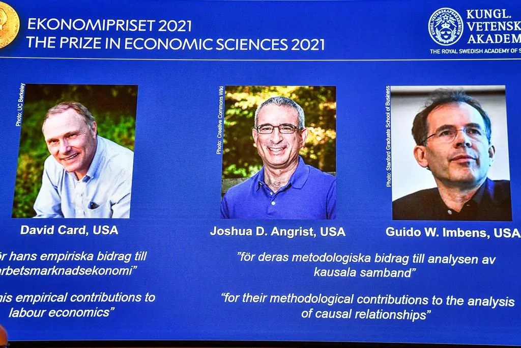 From left, on the screen are the winners of the 2021 Nobel prize for economics; David Card of the University of California at Berkeley; Joshua Angrist from the Massachusetts Institute of Technology; and Guido Imbens from Stanford University, announced during a press conference at the Royal Swedish Academy of Sciences, in Stockholm, Sweden, on Oct. 11, 2021. (Claudio Bresciani/TT via AP)