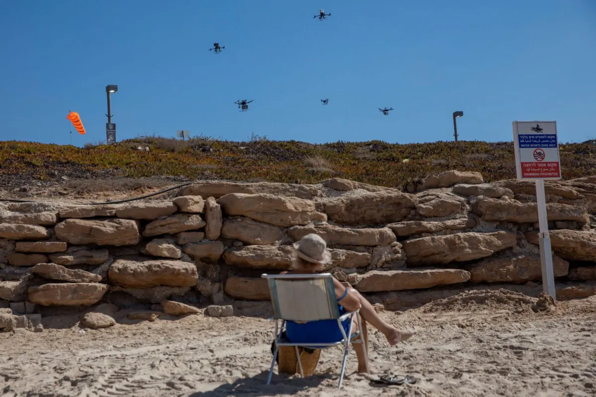 A woman looks at drones carrying goods as part of the National Drone Initiative test operation over Tel Aviv, Israel, on Oct. 11, 2021. (Oded Balilty/AP Photo)