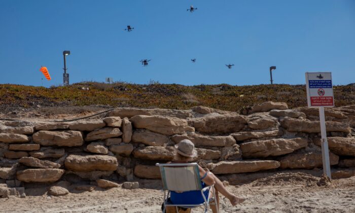 A woman looks at drones carrying goods as part of the National Drone Initiative test operation over Tel Aviv, Israel, on Oct. 11, 2021. (Oded Balilty/AP Photo)