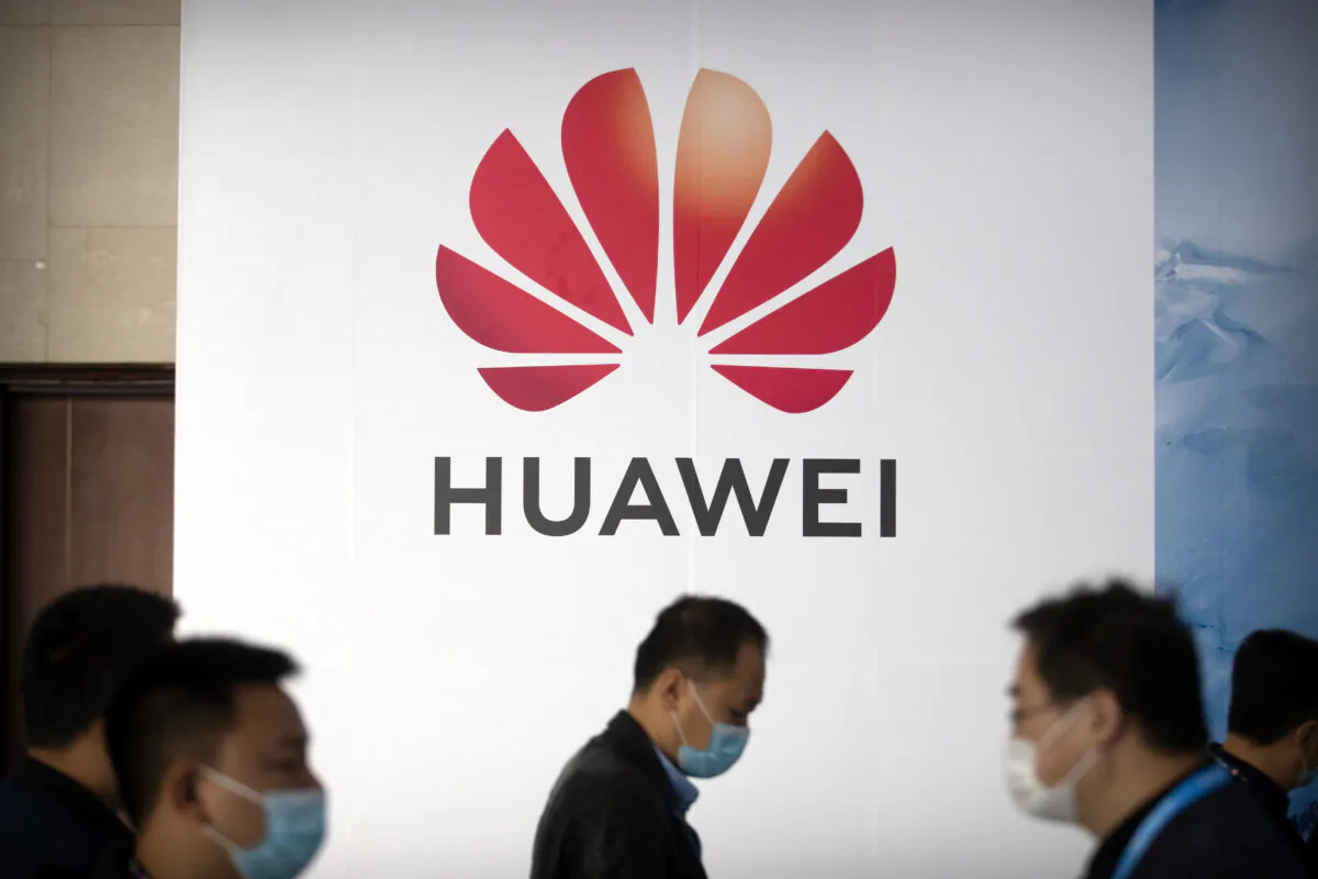 People walk past a billboard advertising Chinese tech company Huawei at the PT Expo in Beijing on Oct. 14, 2020. (Mark Schiefelbein/AP Photo)