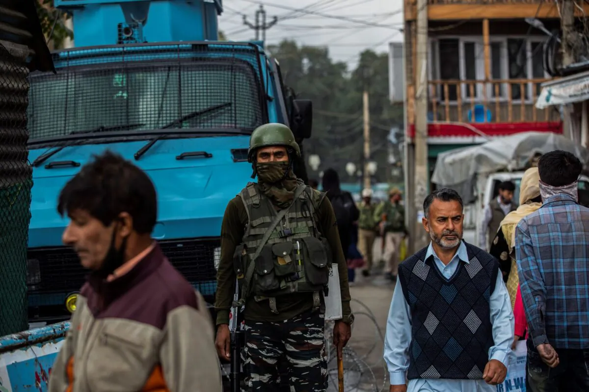 An Indian paramilitary soldier guards as a Kashmiris walk at a busy market in Srinagar, Kashmir, on Oct. 11, 2021. (Mukhtar Khan/AP Photo)