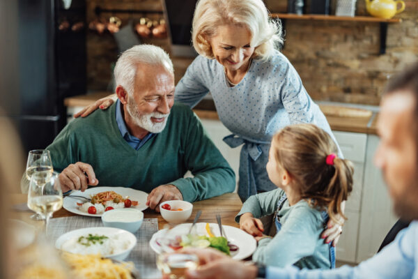 Happy,Senior,Couple,And,Their,Granddaughter,Communicating,During,A,Meal