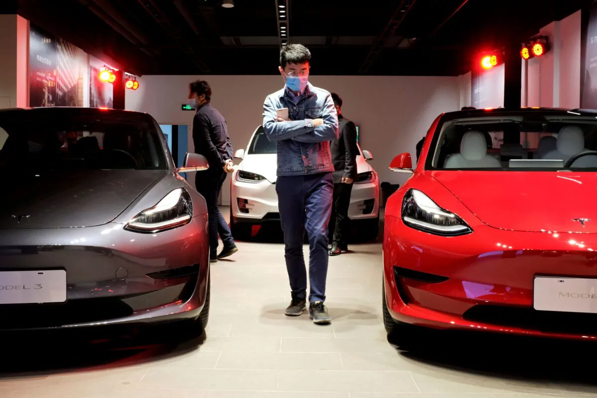 A man walks by Tesla Model 3 sedans and Tesla Model X sport utility vehicle at a new Tesla showroom in Shanghai on May 8, 2020. (Yilei Sun/Reuters)